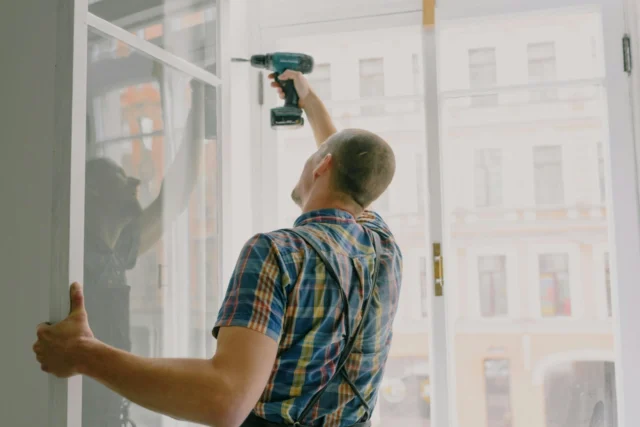 A man with a drill fixing a window for home renovations